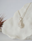 Left side angle close-up of minimalist rainbow moonstone bead necklace highlighting handcrafted soft silver wire wrap and pendant profile.