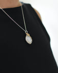 Model wearing rainbow moonstone necklace for women on sterling silver chain, mixed metal wire wrapped pendant (June birthstone).