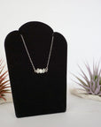 Right angle view of rainbow moonstone and freshwater pearl bar necklace in 925 sterling silver on jewelry display