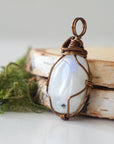 Left angle close-up of rainbow moonstone pendant showing handcrafted antique bronze copper wire wrapping and natural stone detail