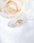 Left angle close-up of rainbow moonstone cabochon pendant with sterling silver and 14k gold filled wire wrap detail.