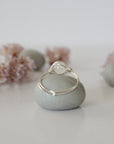 Back view of sterling silver wire wrapped rainbow moonstone ring, minimalist band and handcrafted wrap detail.