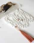 Detailed view of rainbow moonstone and moonstone bead mala necklace featuring 108 beads, rose quartz guru stone, and earthy brown tassel.