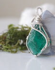 Left angle view of emerald necklace for women with natural raw emerald and detailed sterling silver wire wrapping