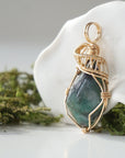 Side angle detail of natural emerald pendant highlighting intricate artisan wrapping in 14k gold-filled wire.