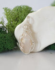 Front view of raw Ethiopian opal pendant — natural unpolished opal stone with colour play, hand-wrapped in detailed 925 sterling silver wire, handcrafted artisan jewelry