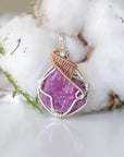 Detailed front view of raw pink ruby pendant in sterling silver and 14k rose gold filled. Unique wire wrapped July birthstone jewelry by Designs by Nature Gems.