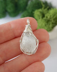 Simple raw rainbow moonstone pendant shown in hand for size reference