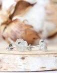Right angle close-up of raw rainbow moonstone stud earrings highlighting organic stone shape and minimalist sterling silver post setting.