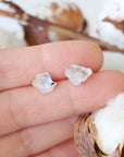 Raw rainbow moonstone stud earrings in hand showing natural 6–9mm moonstone stones on 925 sterling silver posts, June birthstone studs.