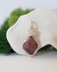 Front view of a natural raw ruby pendant hand-wrapped in soft silver finish over copper wire — July birthstone necklace for women