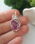 Handmade raw ruby pendant held in hand showing size — natural pink ruby stone wire wrapped in 925 sterling silver, approx. 1 inch, one of a kind