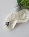 Simple raw sapphire necklace with silver plated brass chain laying flat