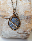 Back view of raw sapphire pendant showing the detail of antique bronze and dark silver wire-wrapping — one-of-a-kind artisan crystal jewelry