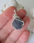 Raw sapphire pendant held in hand to show size — 925 sterling silver wire wrap, women's handcrafted crystal necklace by Designs by Nature Gems