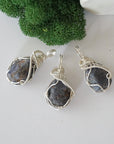 Three raw sapphire pendants showing natural variation in stone size, shape, and blue-grey tone — each one of a kind, September birthstone, 925 sterling silver wire wrapped, Designs by Nature Gems