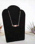 Right angle view of ruby and freshwater pearl bar necklace in 925 sterling silver on jewelry display