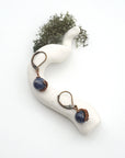 Bird’s eye view of sapphire drop earrings laying flat on a display, showing detailed wire wrapping and gemstone color.