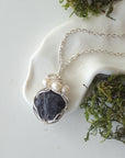 Handmade silver wire wrapped sapphire and freshwater pearl necklace laying flat on a silver plated chain, artisan jewelry for women