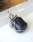 Right-angle detail of natural sapphire pendant showing artisan wire-wrapping in dark silver — handcrafted crystal necklace