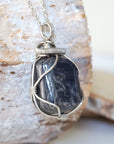 Right-angle detail of natural sapphire pendant showing artisan wire-wrapping in dark silver — white gold plated chain, handcrafted crystal necklace