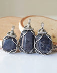 Three natural sapphire pendants showing variation in size, shape, and depth of colour — each dark silver wire-wrapped necklace is individually handcrafted and one of a kind