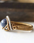 Side-angle detail of natural sapphire ring showing the artisan wire wrapping in antique bronze and dark silver finish