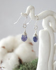 Side view of sapphire sterling silver drop earrings showing wire wrapped natural faceted sapphire, artisan craftsmanship, on a display – Designs by Nature Gems