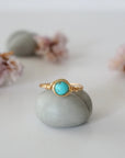 Front view of simple turquoise ring in gold plated copper showing 6mm polished stone and handmade wire wrapping detail