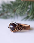 Wire wrapped garnet ring in mixed metal copper with a geometric wire design, shown as the main product image