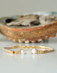 Front view of a women’s pearl and moonstone leather bracelet with freshwater pearls and rainbow moonstone centerpiece