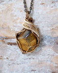 Yellow tiger's eye necklace front view — polished-raw stone in antique bronze and gold wire wrap, handmade crystal pendant