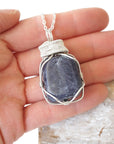 Sapphire necklace for men in hand for size reference – polished raw sapphire, 925 sterling silver wire, September birthstone, masculine design.