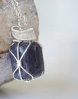 Right angle close-up of sapphire necklace for men – detailed 925 sterling silver wire wrapping, genuine sapphire, September birthstone.