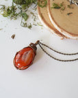 Handcrafted raw carnelian necklace laying flat – artisan bronze copper wire wrapping, Virgo zodiac birthstone jewelry for all genders, Designs by Nature Gems.
