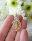 Raw citrine pendant necklace held in hand showing size of wire wrapped sterling silver jewelry November birthstone
