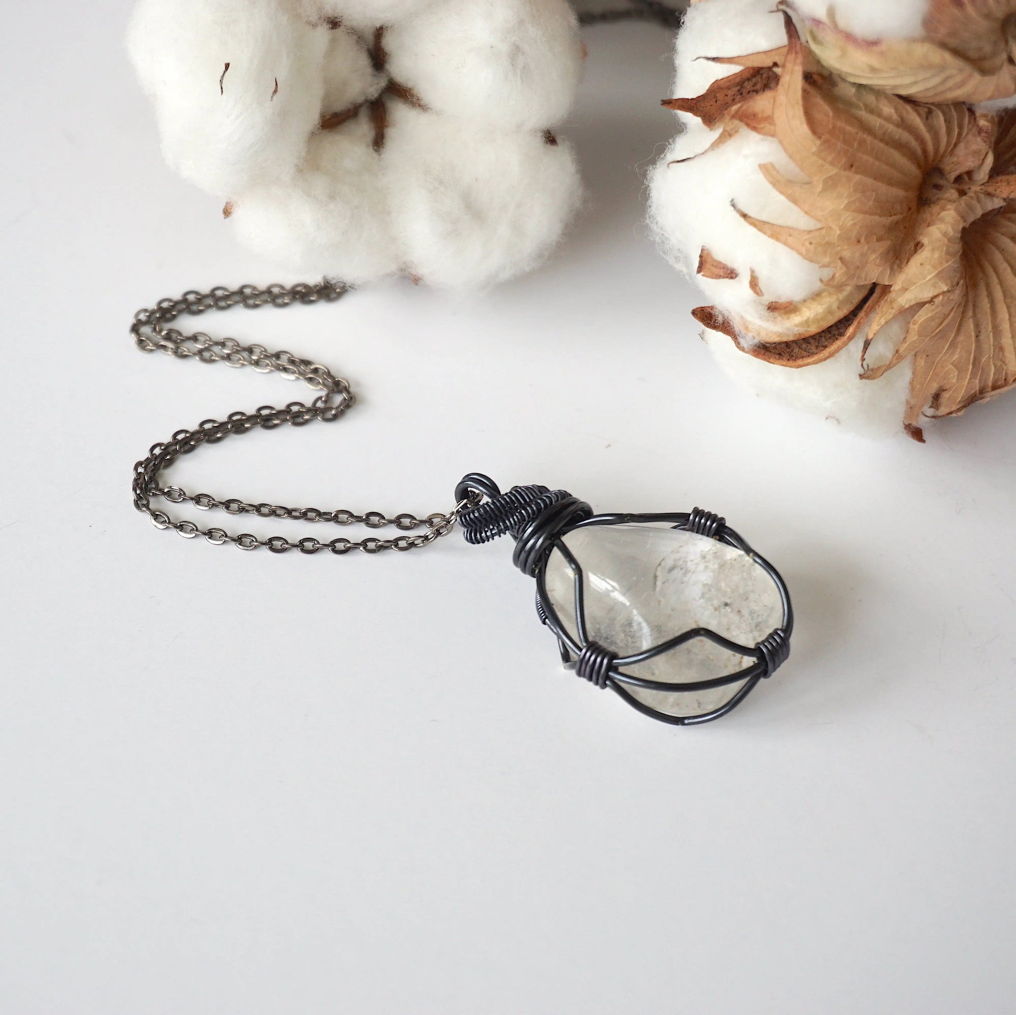 Handcrafted clear quartz necklace for women, laying flat on gunmetal chain – artisan wire wrapped, April birthstone, natural crystal pendant.