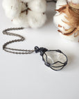 Handcrafted clear quartz necklace for women, laying flat on gunmetal chain – artisan wire wrapped, April birthstone, natural crystal pendant.