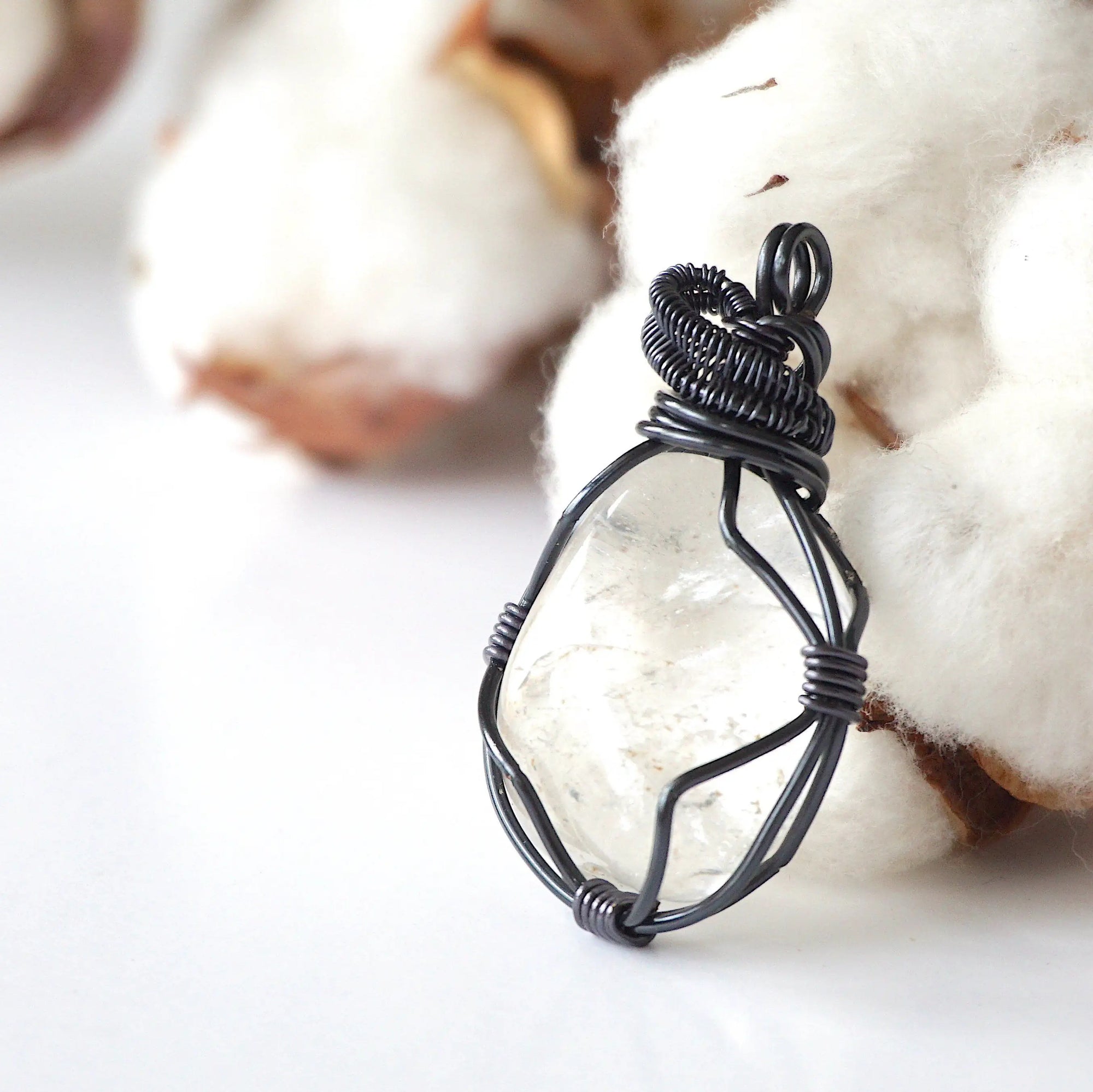 Left angle close-up of clear quartz pendant – highlighting unique wire-wrapped artistry, gunmetal copper, April birthstone.