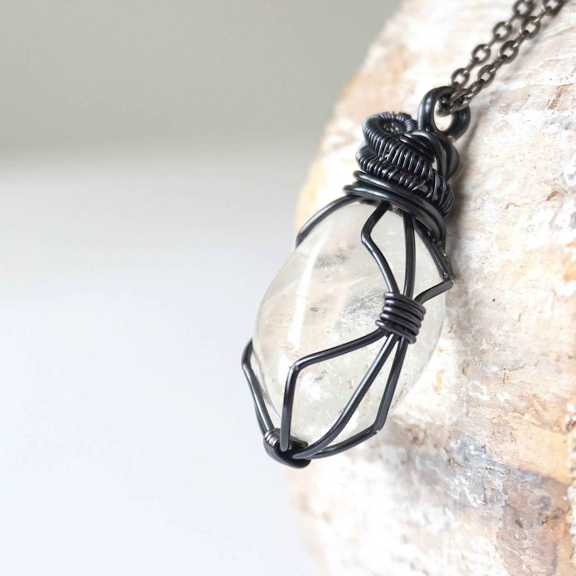 Left angle close-up of clear quartz pendant for men – highlighting unique wire-wrapped artistry, gunmetal copper, April birthstone.