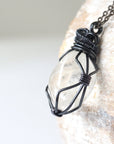 Left angle close-up of clear quartz pendant for men – highlighting unique wire-wrapped artistry, gunmetal copper, April birthstone.