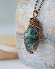 Left angle close-up of emerald necklace – highlighting unique wire-wrapped artistry, raw emerald crystal, gender-inclusive jewelry.