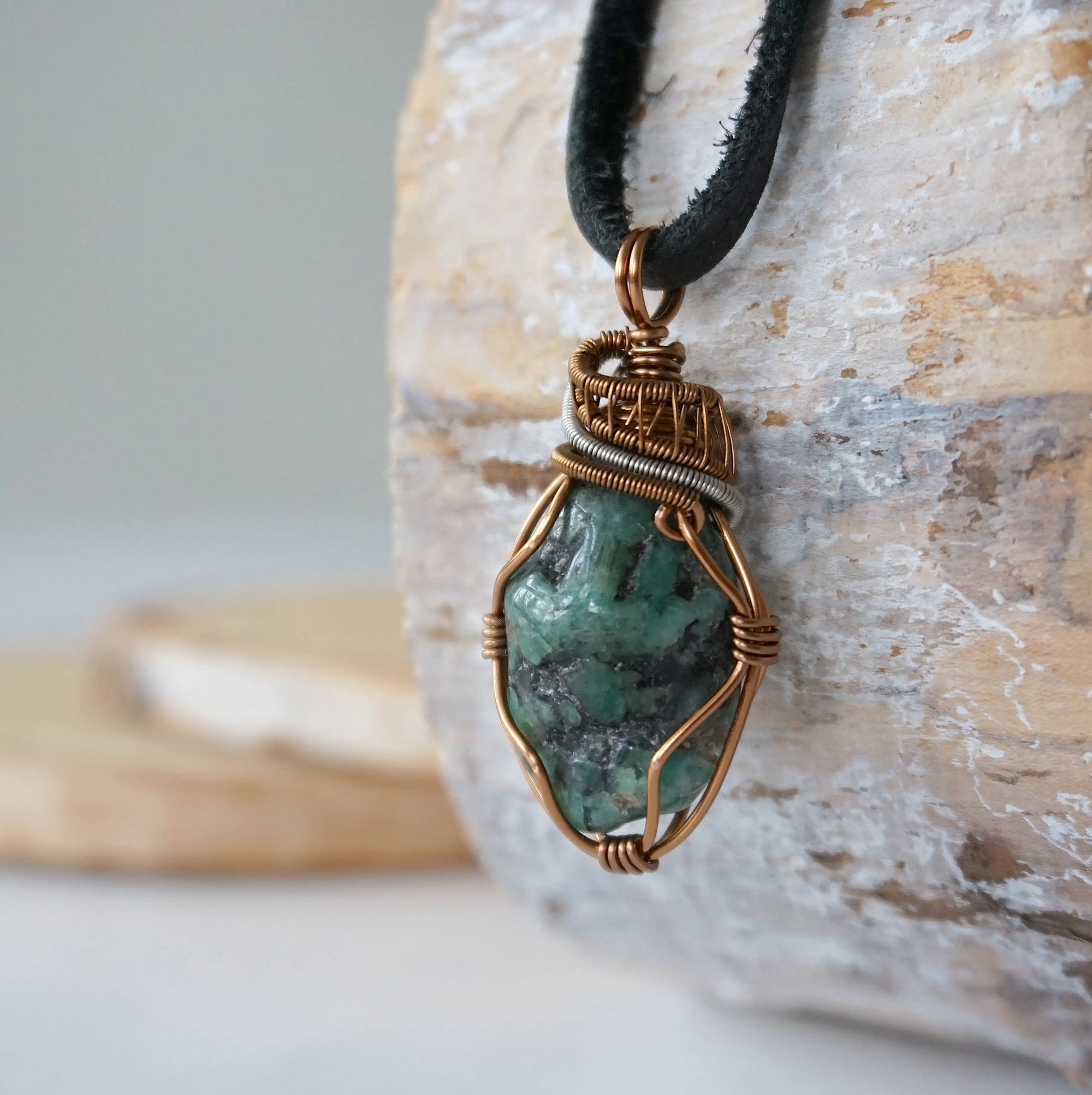 Left angle close-up of men's emerald necklace – highlighting unique wire-wrapped artistry, raw emerald, black leather cord.