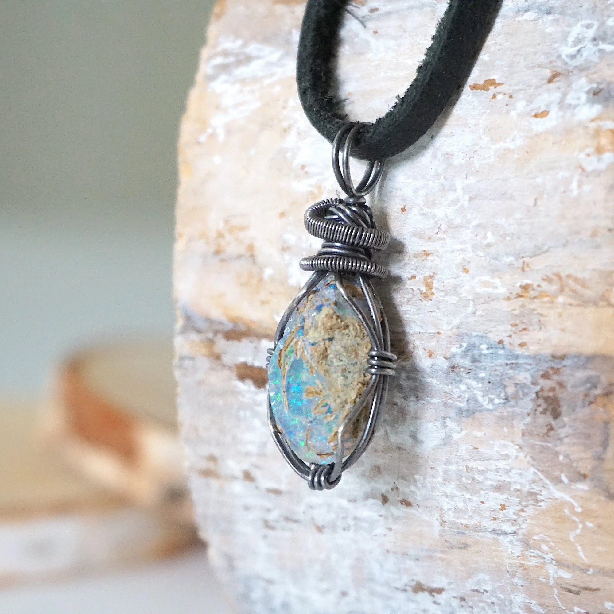 Left angle close-up of men's opal necklace – highlighting unique wire-wrapped artistry, Ethiopian fire opal, black leather cord.