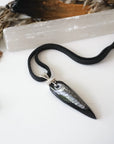 Handcrafted Orthoceras fossil necklace for men, laying flat on black leather cord – genuine ancient ocean fossil, minimalist 925 sterling silver wire wrapping.