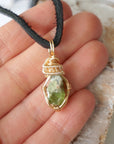 Raw peridot necklace for men in hand – size reference, showcases natural green stone and artisan wire wrapping.