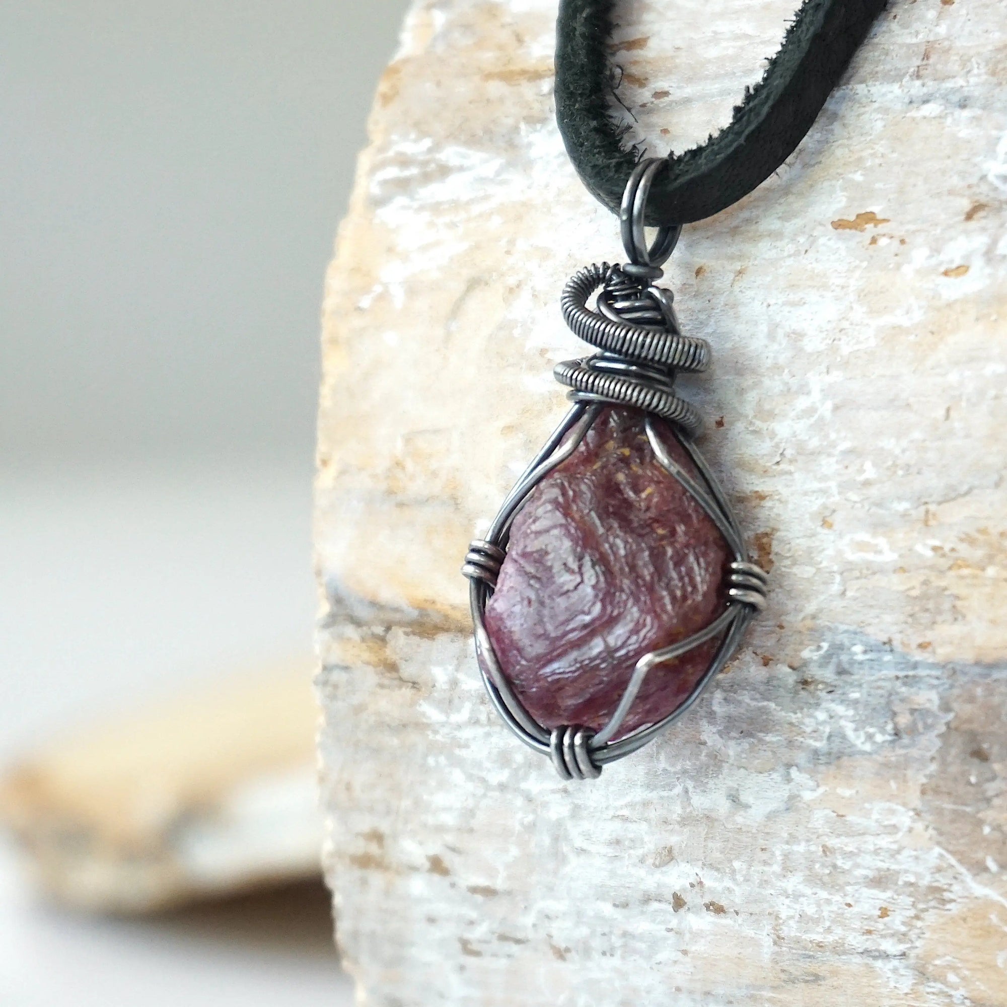 Left angle close-up of men's ruby necklace – highlighting unique wire-wrapped artistry, red ruby, black leather cord.