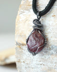 Left angle close-up of men's ruby necklace – highlighting unique wire-wrapped artistry, red ruby, black leather cord.
