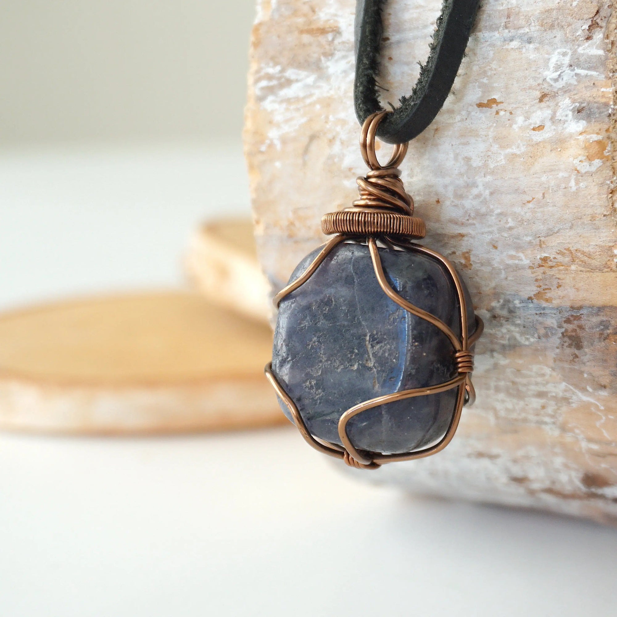 Left angle close-up of men's sapphire necklace – highlighting unique wire-wrapped artistry, genuine sapphire, black leather cord.