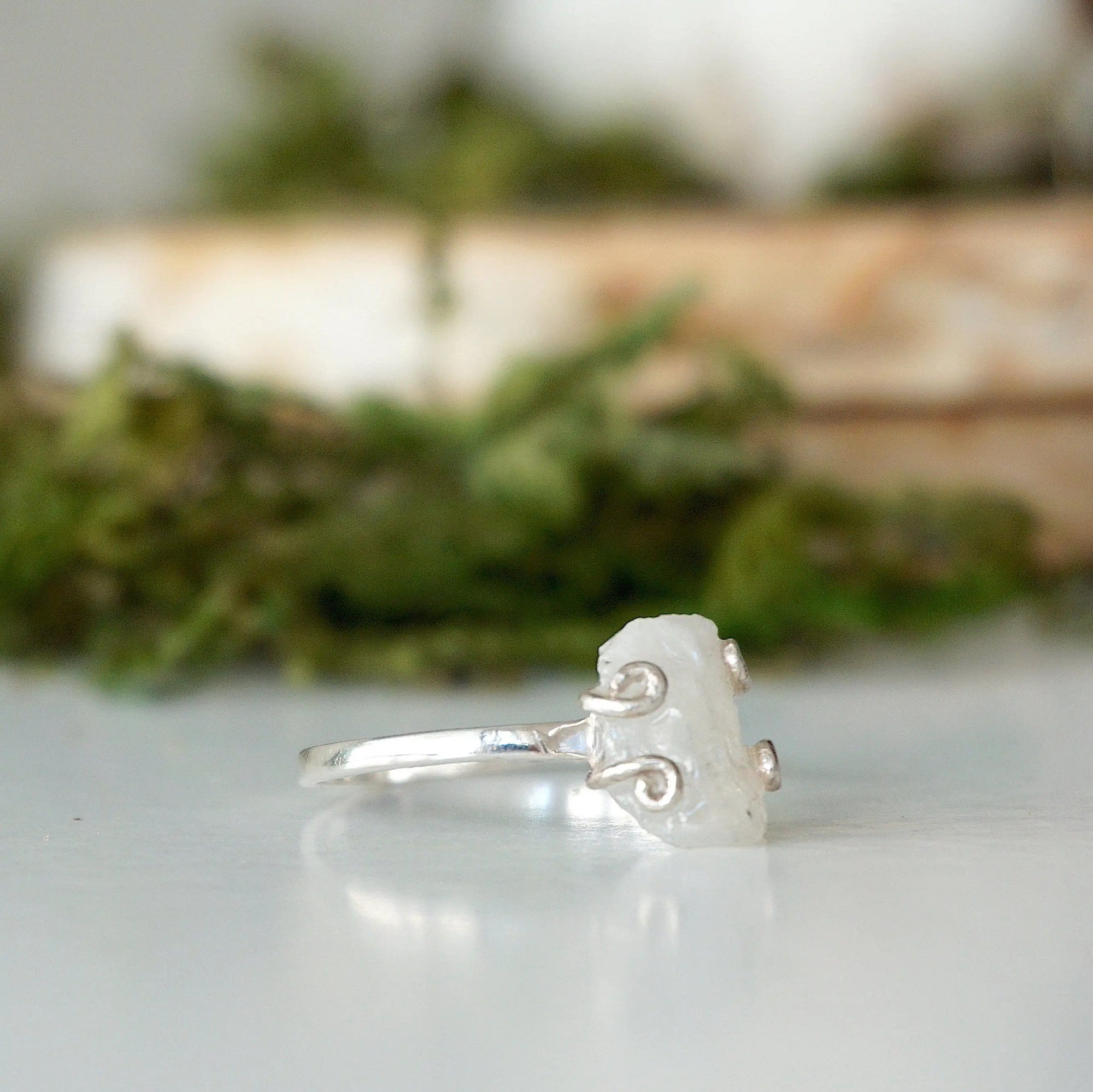 Right side angle close-up of adjustable raw rainbow moonstone ring showing sterling silver prongs and natural stone shape.